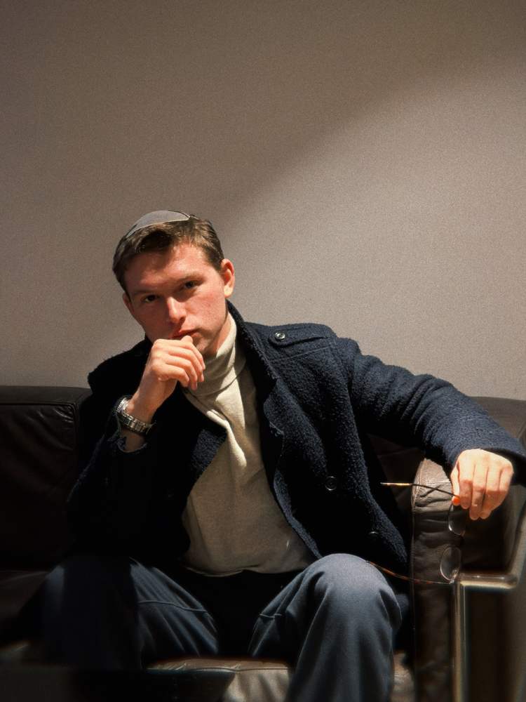 Liam Ratner seated, holding his glasses