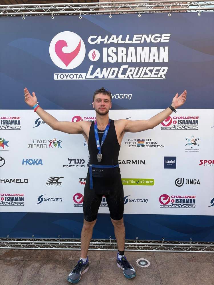 Netanel at the finish line of Challenge Isaman, arms raised, finisher's medal around his neck